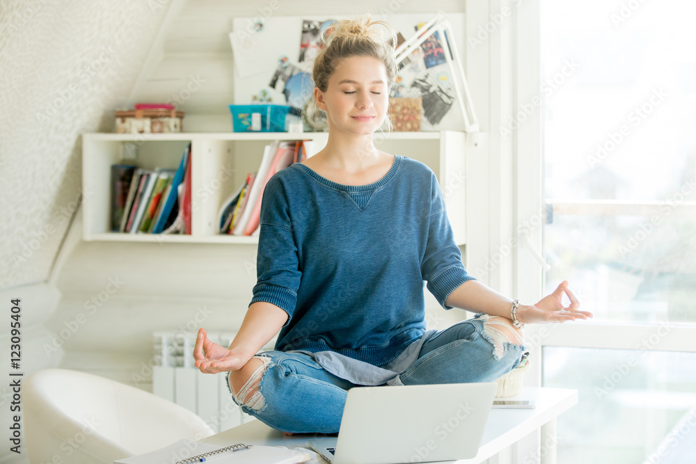 Portrait of an attractive woman on the working table. Lotus pose. Motivation photo Portrait of an attractive woman on the working table. Lotus pose. Motivation photo