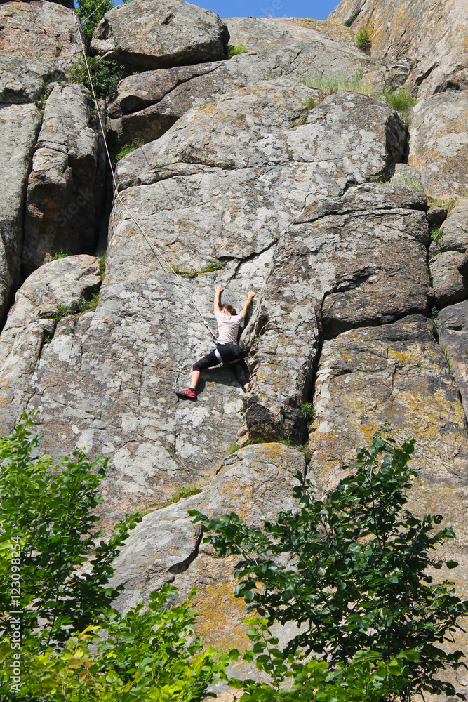 Woman rock climber climbs on a rock