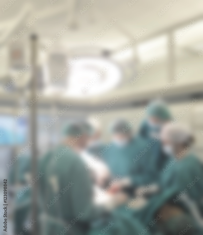 Surgical team operating on patient in theater in hospital- blurred.