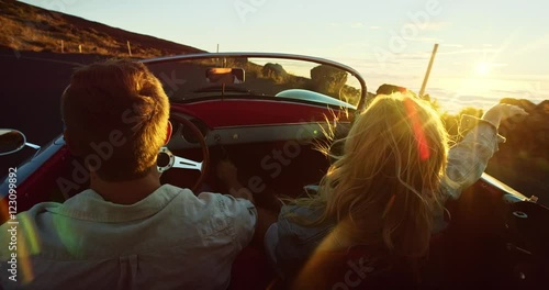 Wallpaper Mural Happy couple driving on country road into the sunset in classic vintage sports car Torontodigital.ca