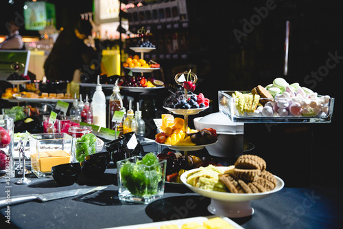 Rich sweets buffet covered with black tablecloth stands in the n