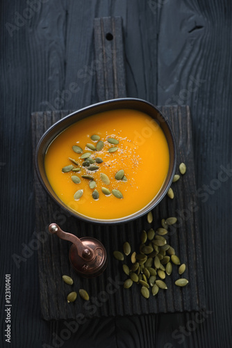 Above view of pumpkin cream-soup over black wooden background