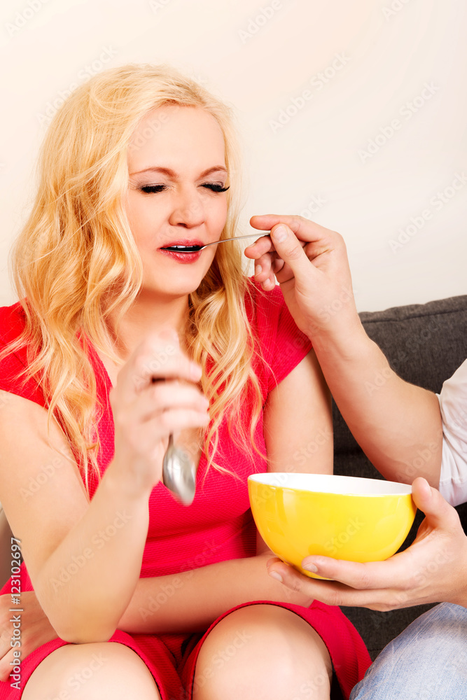 Man feeds his girlfriend on the sofa Man feeds his girlfriend on the sofa