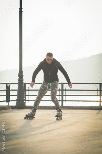 young man with inline skates ride in summer park seafront outdoor rollerskater