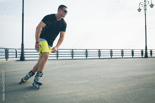 Obraz na plátne young man with inline skates ride in summer park seafront outdoor rollerskater