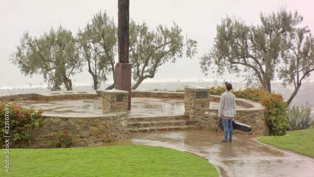 young man boy musician walks in rain and looks up at large cross outside young man boy musician walks in rain and looks up at large cross outside