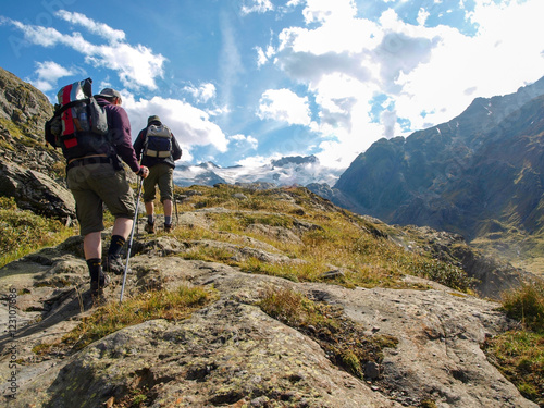 Young hikers trekking in alps, Switzerland, with mountains in th