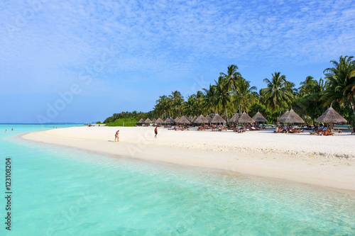 white beach with coconut palms and bungalows on the Maldives