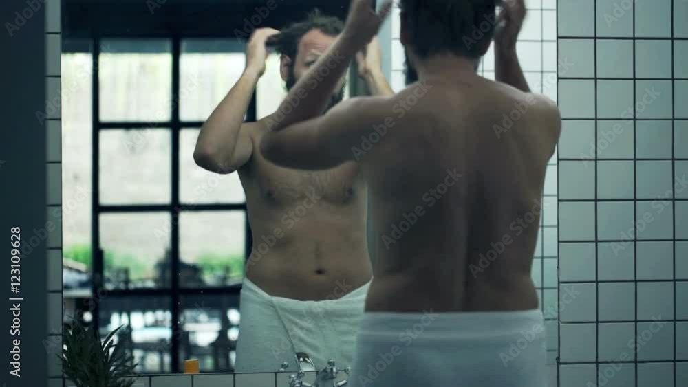 Young man checking his look in front mirror in bathroom
Young man checking his look in front mirror in bathroom