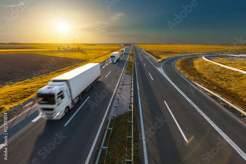Three trucks on the freeway at idyllic sunset