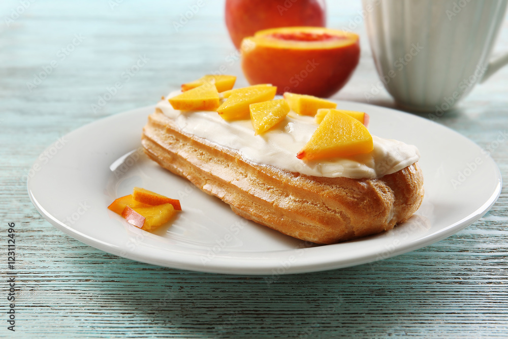 Delicious eclair with peach slices on plate Delicious eclair with peach slices on plate