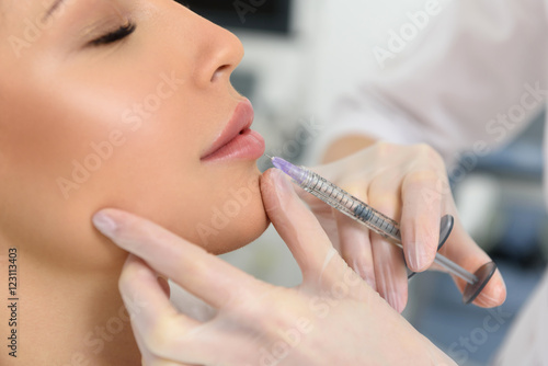 Obraz na plátně Close-up cosmetologist giving lip injection to woman