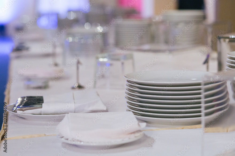 White plates stand in a heap on the dinner table White plates stand in a heap on the dinner table