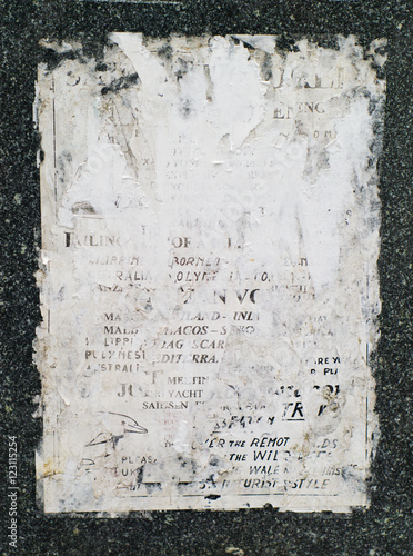 closeup shot of old, faded, and torn posters on granite wall