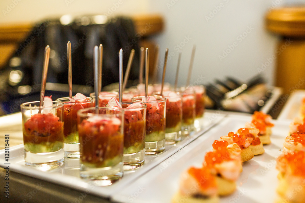 Red fish appetizers with green sauce put in glass shots Red fish appetizers with green sauce put in glass shots