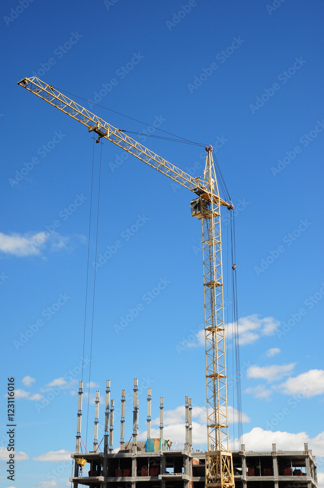 Tower Crane and building construction site with contractor on the top. Industrial building.