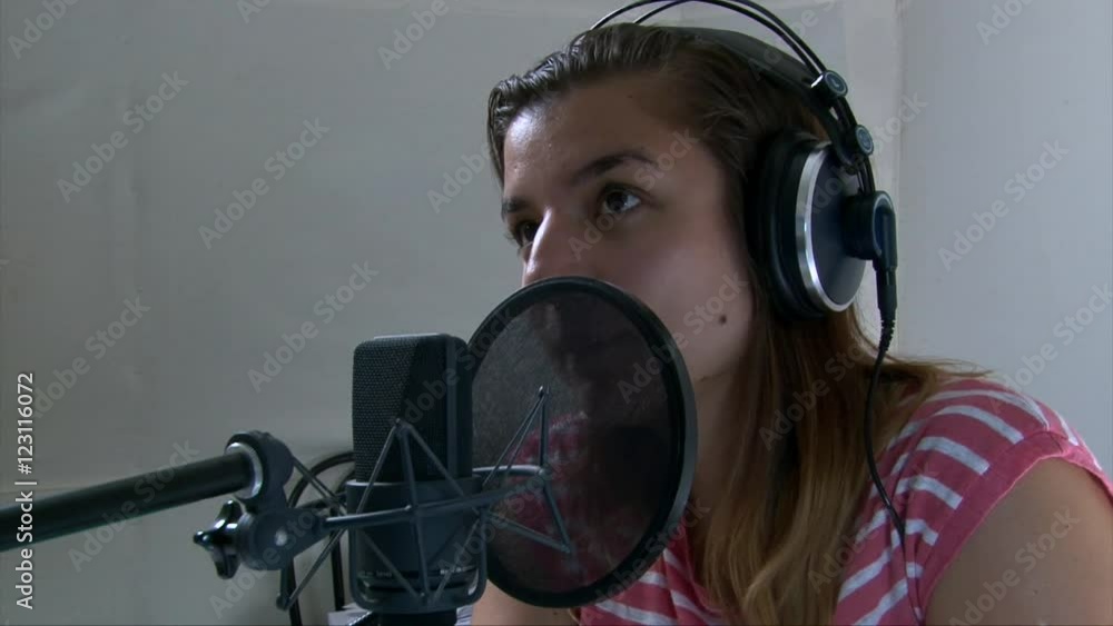 Teen girl sings at the professional audio studio into a microphone, portrait shot Teen girl sings at the professional audio studio into a microphone, portrait shot
