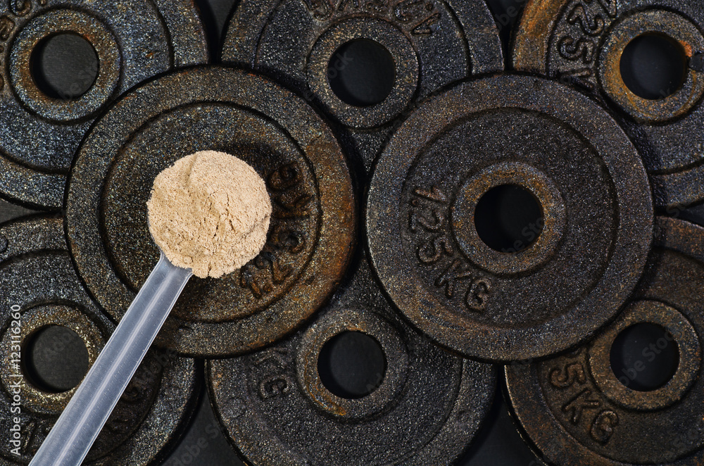 Scoop of whey protein on black background. Top view