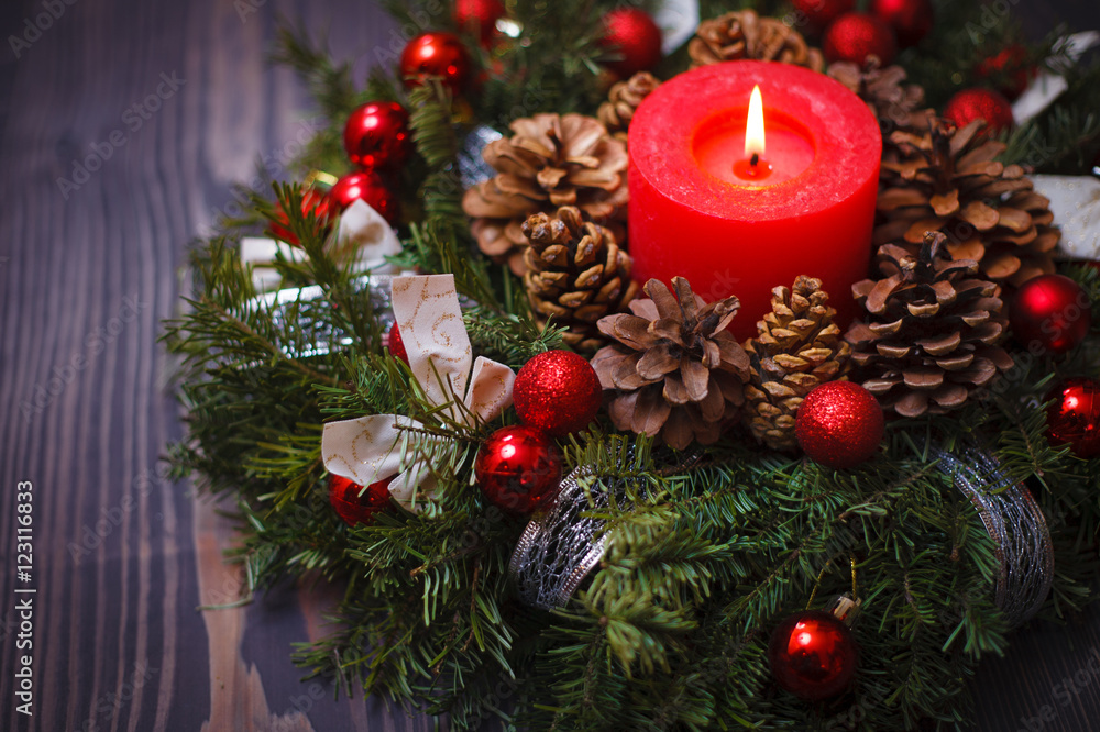 Red candle in a wreath of pine branches with Christmas balls Red candle in a wreath of pine branches with Christmas balls