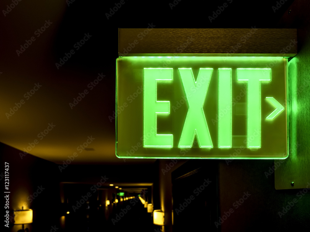 Close-up view of an illuminated green exit sign in a hotel Close-up view of an illuminated green exit sign in a hotel