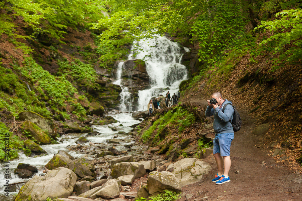 Man standing at the waterfall and making photos