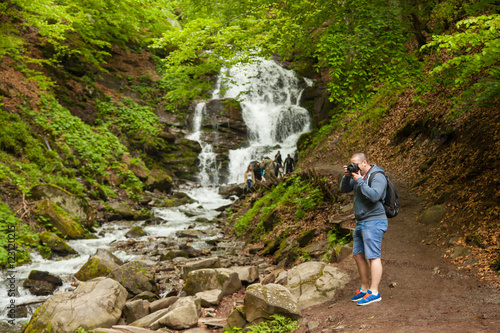 Man standing at the waterfall and making photos