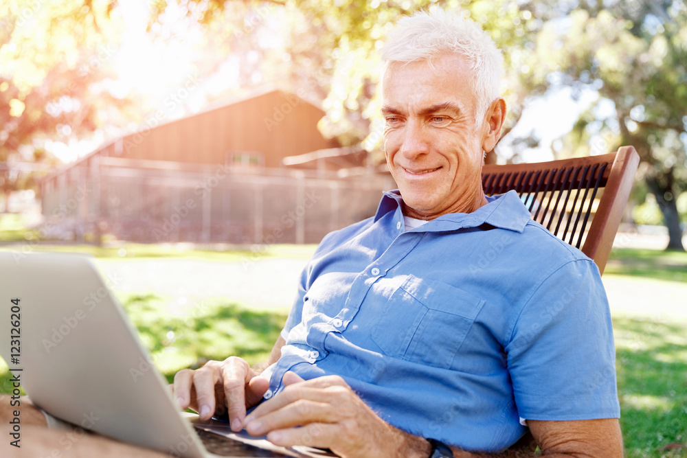 Senior man with notebook sitting in the park Senior man with notebook sitting in the park