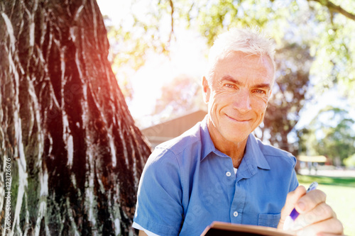 Senior man sittingin park while reading book photo