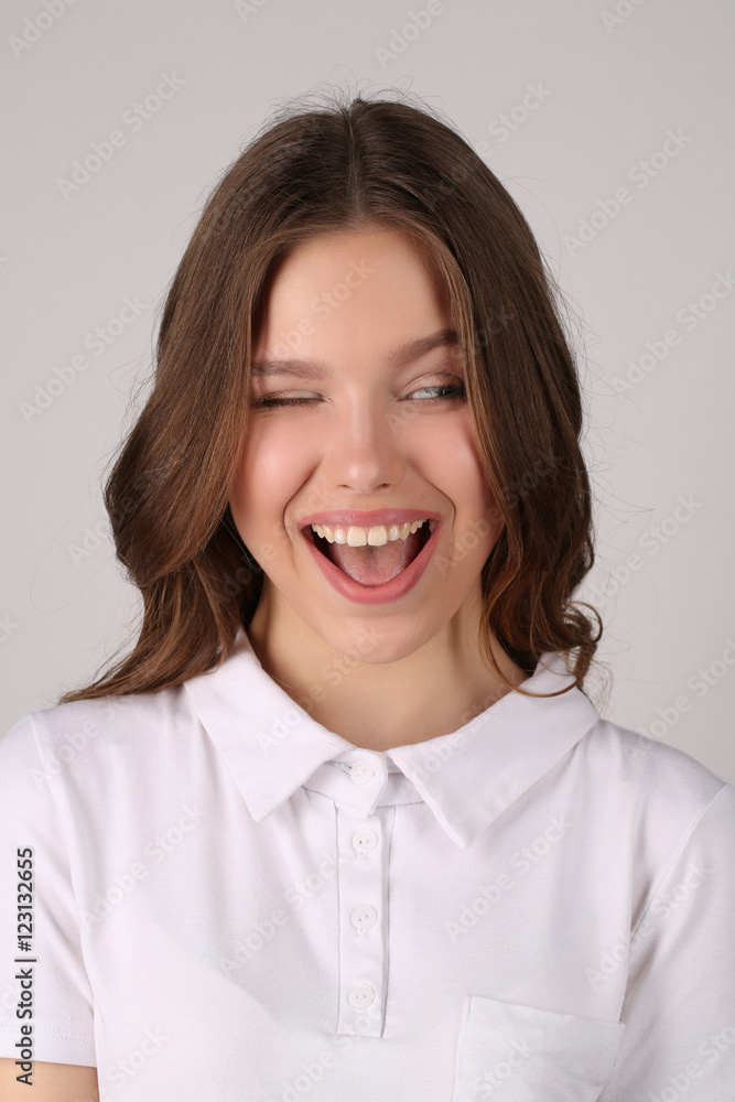 Girl in T-shirt winking. Close up. White background