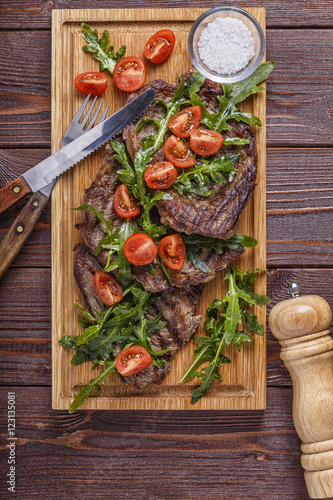 Steaks with arugula and tomatoes.