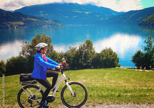 woman cycling on an electric bike beside a beautiful lake/biking