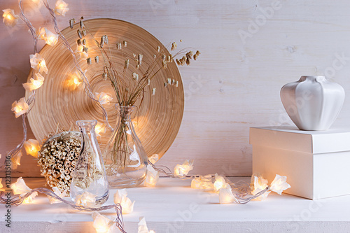 Tablou pe pânză Christmas home decoration with burning lights on white wooden background
