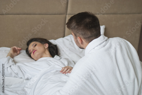 Side view of man looking at woman while lying in bed 