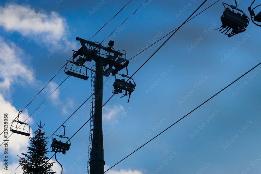 few four seats ski snowboard chairlift lift at ski resort with groups of people and beautiful clody blue sky on the background few four seats ski snowboard chairlift lift at ski resort with groups of people and beautiful clody blue sky on the background