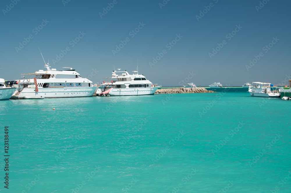 few white yacht near coral reef in the calm blue sea blue cloudless sky