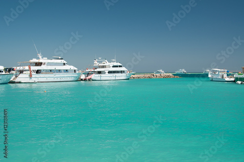 few white yacht near coral reef in the calm blue sea blue cloudless sky © PabloStock