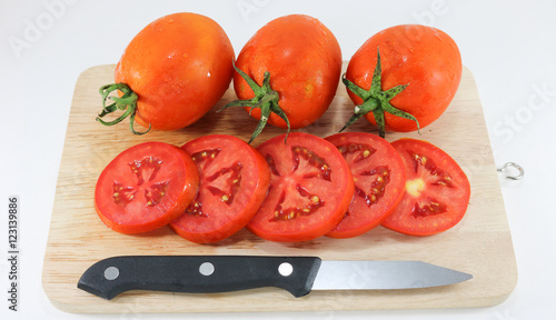 Tomato on wood chopping block with knife white background isolat