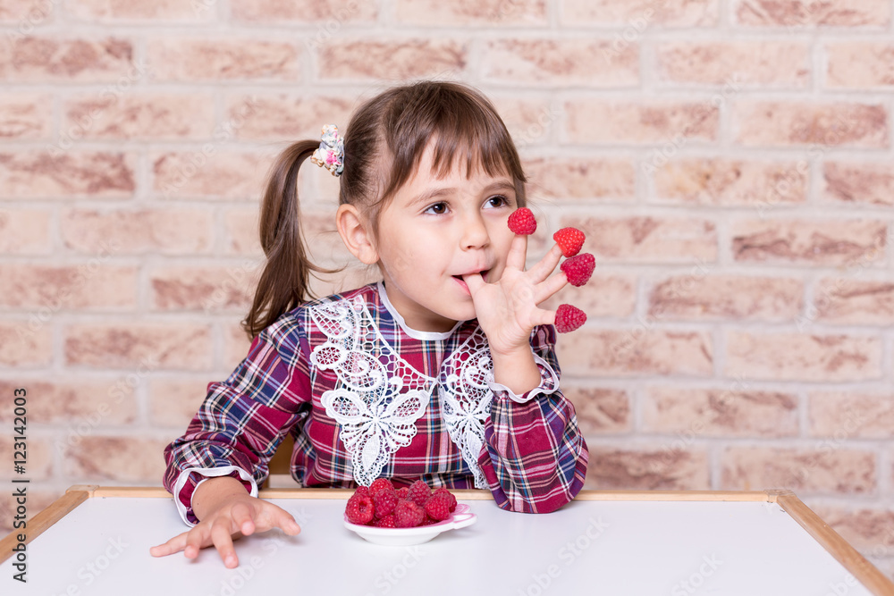 happy little kid girl eating fresh raspberries happy little kid girl eating fresh raspberries