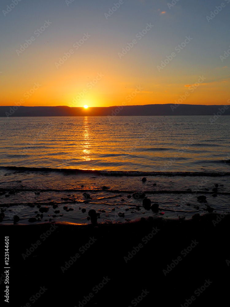 Warm gold and orange sunrise on the shore of the Sea of Galilee , Israel