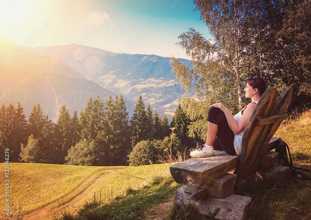 woman sitting on a bench enjoying view over mountains