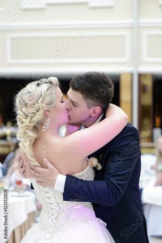 Wedding couple in the restaurant is dancing. Beautiful model girl in white dress. Handsome man in suit. Beauty bride with groom. Female and male portrait. Woman with lace veil. Lady and guy indoors © pvstory