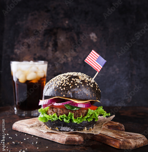Beef Burger with a Black Bun; with lettuce and mayonnaise and ketchup on a dark background.Patriotic 4th of july themed Burgers at picnic.selective focus