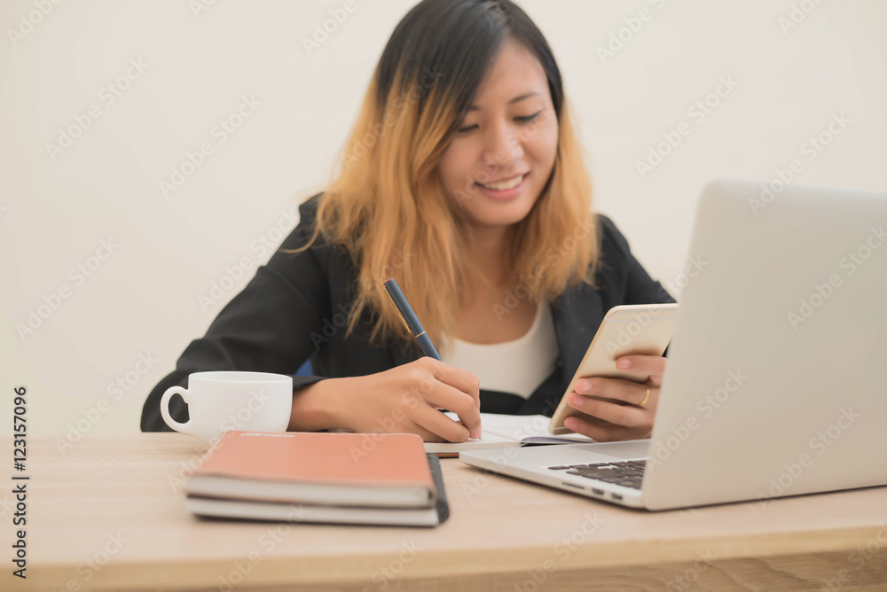 young business woman sitting at workplace and Writing notes in a young business woman sitting at workplace and Writing notes in a