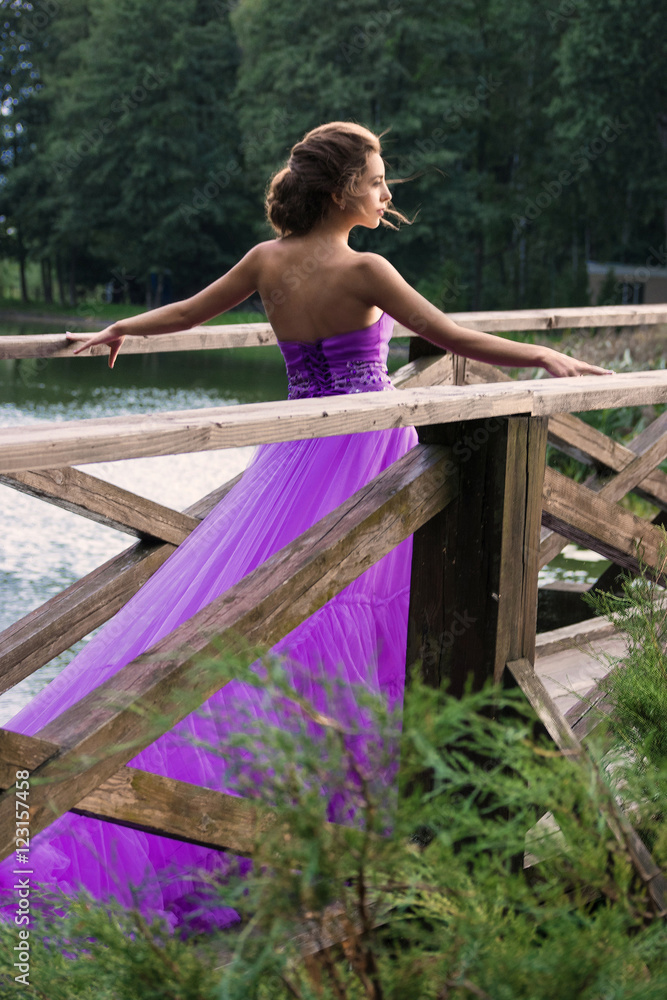 Naklejka premium Beautiful girl in violet dress among in the garden