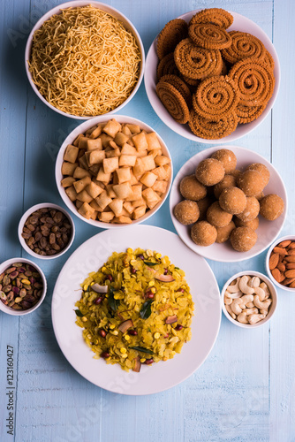 home made tasty Diwali food or Diwali snacks or Diwali sweets like rava laddu, chakli, sev,shankar pale and chivda or chiwada with dry fruits in white bowls, favourite indian diwali recipe photo