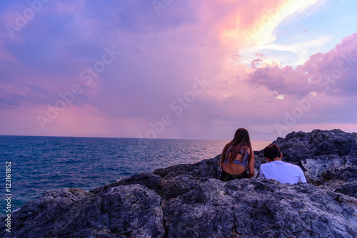 Fototapeta Naklejka Na Ścianę i Meble -  A couple of guys watch the sunset sitting on a rock