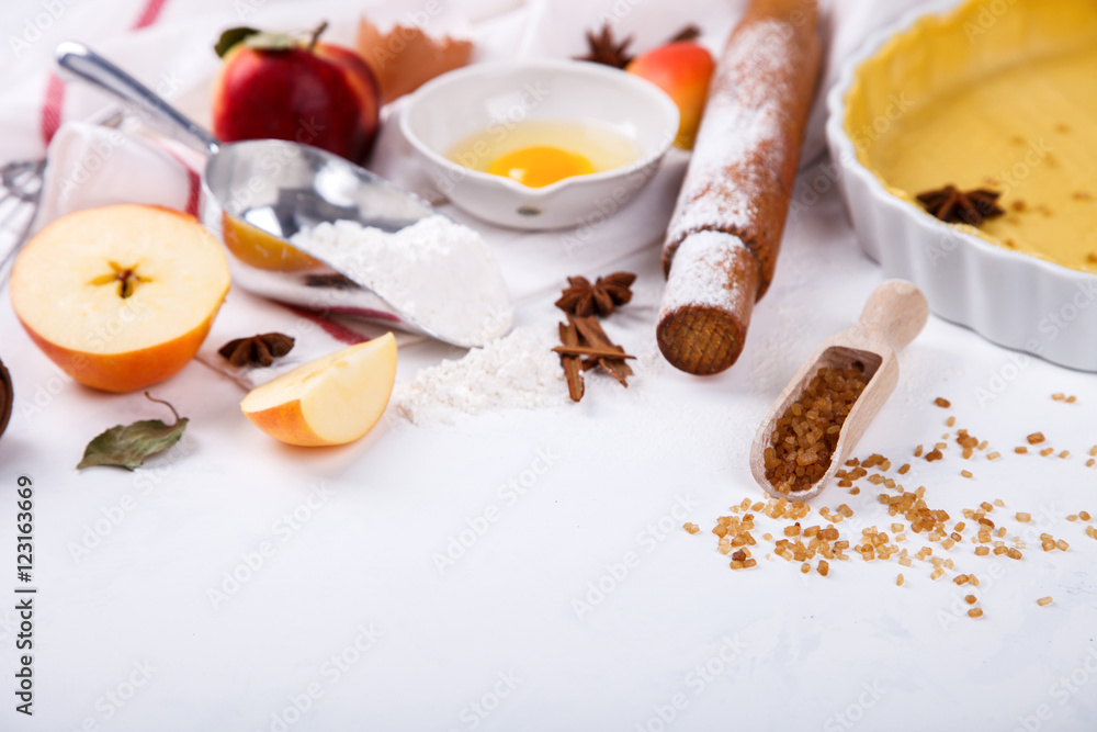 Baking Background. Ingredients for baking Apple Pie - apples,spices ,flour, rolling pin, eggs, egg yolks, butter served, milk on white background.selective focus. Copy space. Baking Background. Ingredients for baking Apple Pie - apples,spices ,flour, rolling pin, eggs, egg yolks, butter served, milk on white background.selective focus. Copy space.
