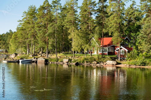 Traditional, red wooden house on a lake in Småland, Sweden, in an early summer morning
