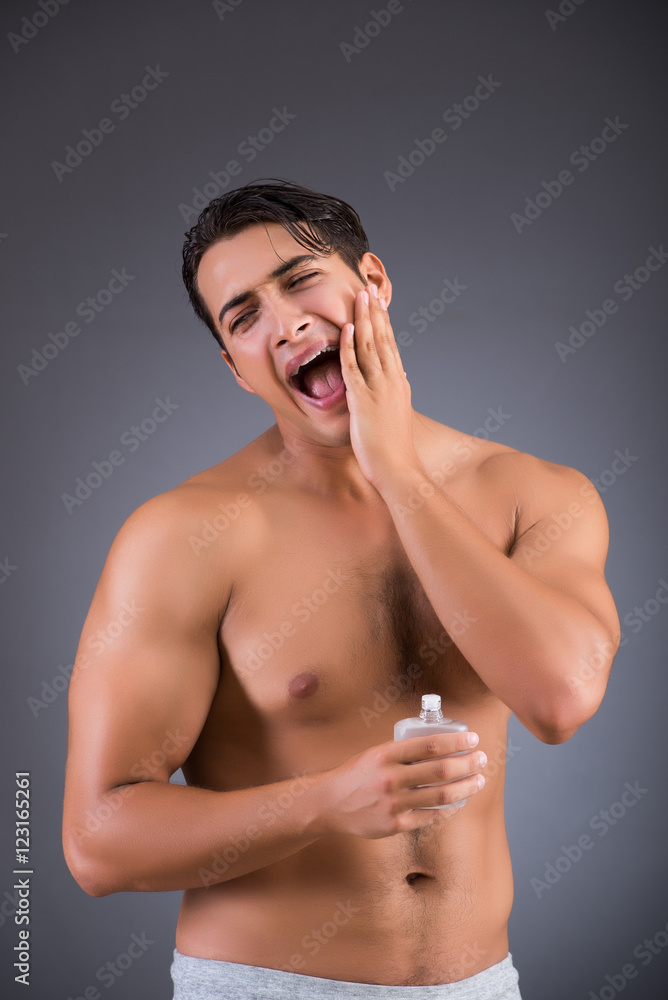 Handsome man applying aftershave afer shaving Handsome man applying aftershave afer shaving
