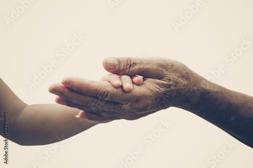 Old female hand holding young baby hand in vintage tone photo